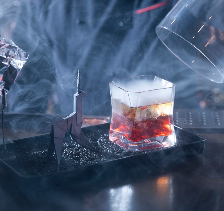 An Arnolfo di Cambio crystal tumbler with a red cocktail surrounded by dry ice smoke