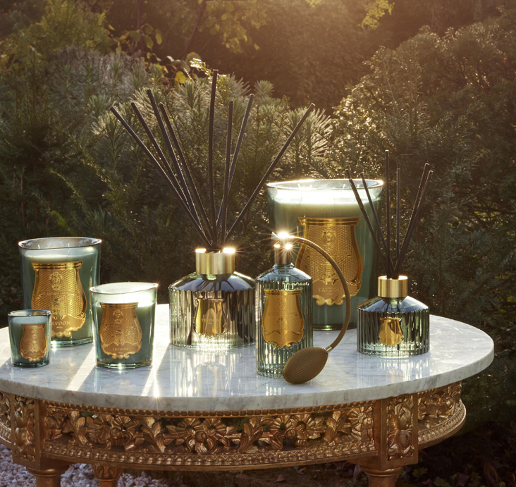 Trudon golden brass candleholders and incense diffusers arranged on a marble surface in warm light