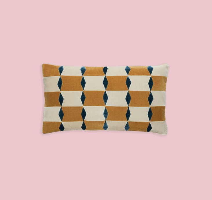 Three Christina Lundsteen cushions in bold geometric patterns in mustard, blue and pink tones on a blush background