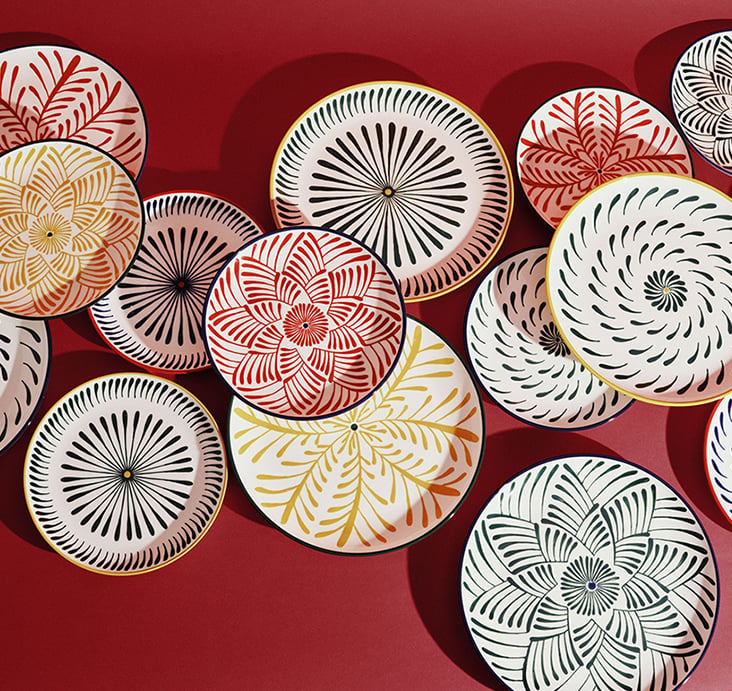 An assortment of Serax 'Bazaar' decorative plates with patterned rims on a red background
